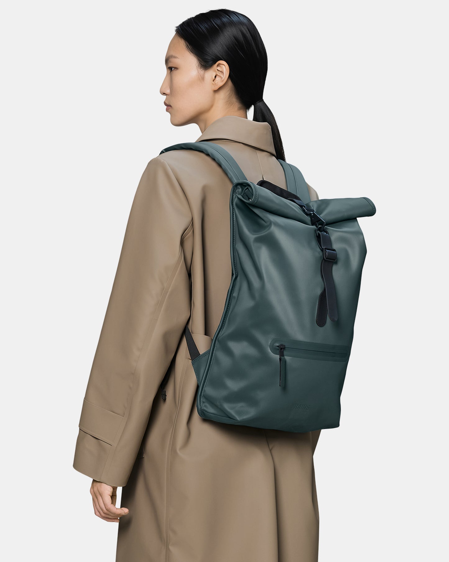 model wearing a Rains Unisex Rolltop Rucksack in 175 Mystique