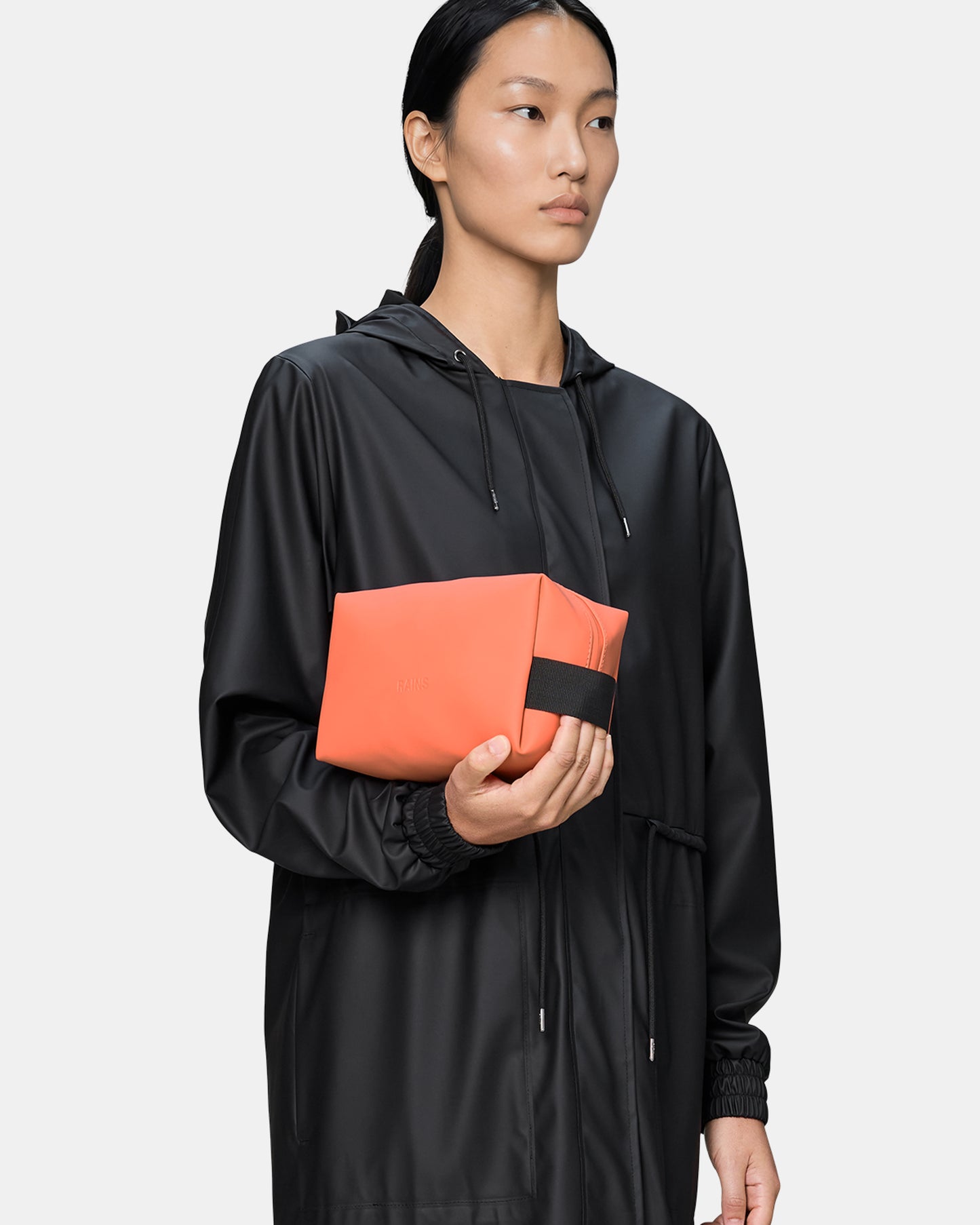 model holding a Rains Wash Bag Small in 174 Ember