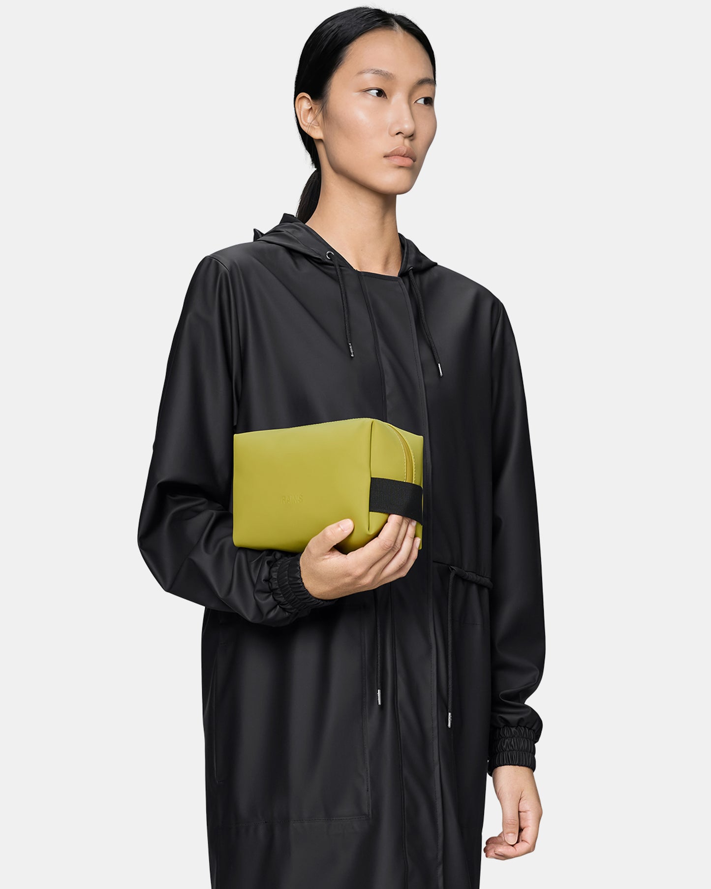model holding a Rains Wash Bag Small in 198 Glow