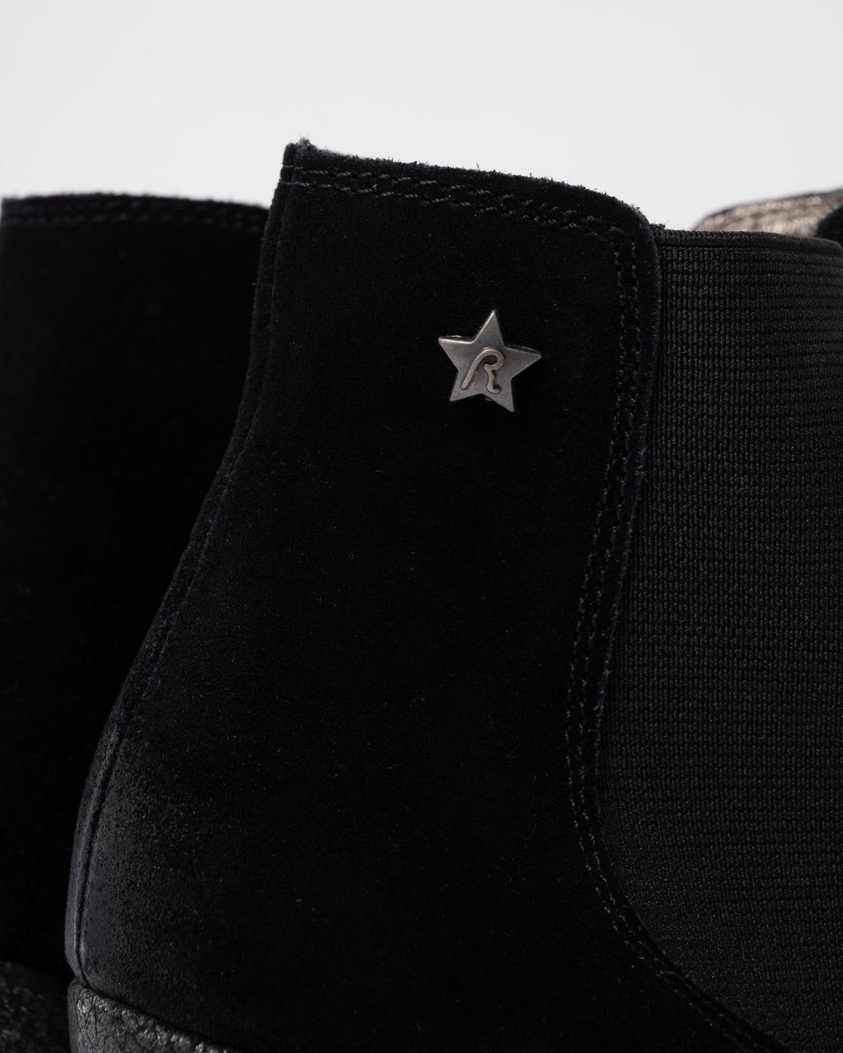 Black sneaker with a star-shaped logo on a light gray background