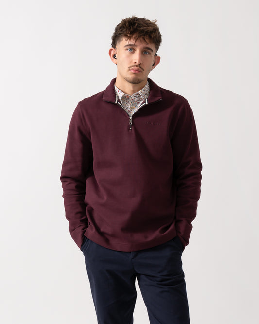 Model wearing a Ted Baker Actos Mens 1/4 Zip Sweatshirt in Maroon