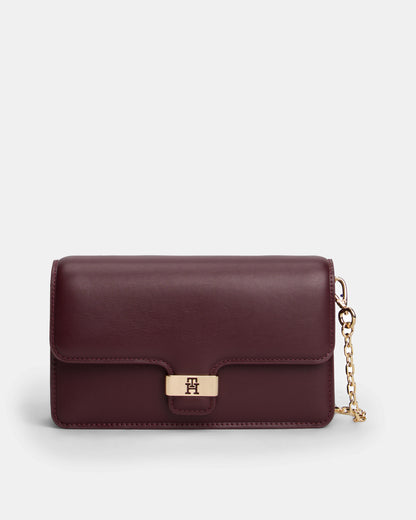 Burgundy Tommy Hilfiger handbag with a gold chain on a light grey background