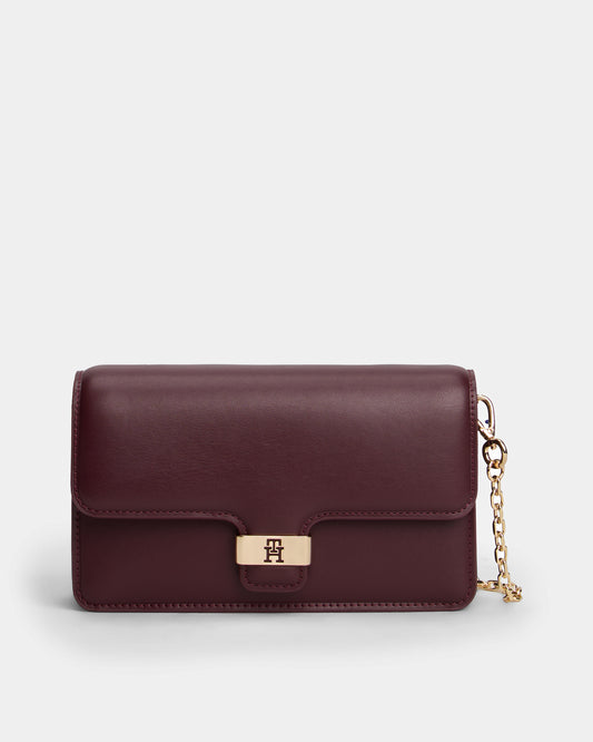 Burgundy Tommy Hilfiger handbag with a gold chain on a light grey background
