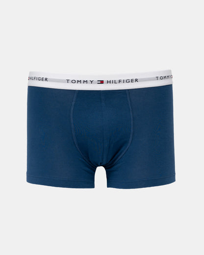A pair of Tommy Hilfiger men's boxer briefs in navy blue, featuring a white elastic waistband with the brand's logo and name printed repeatedly.