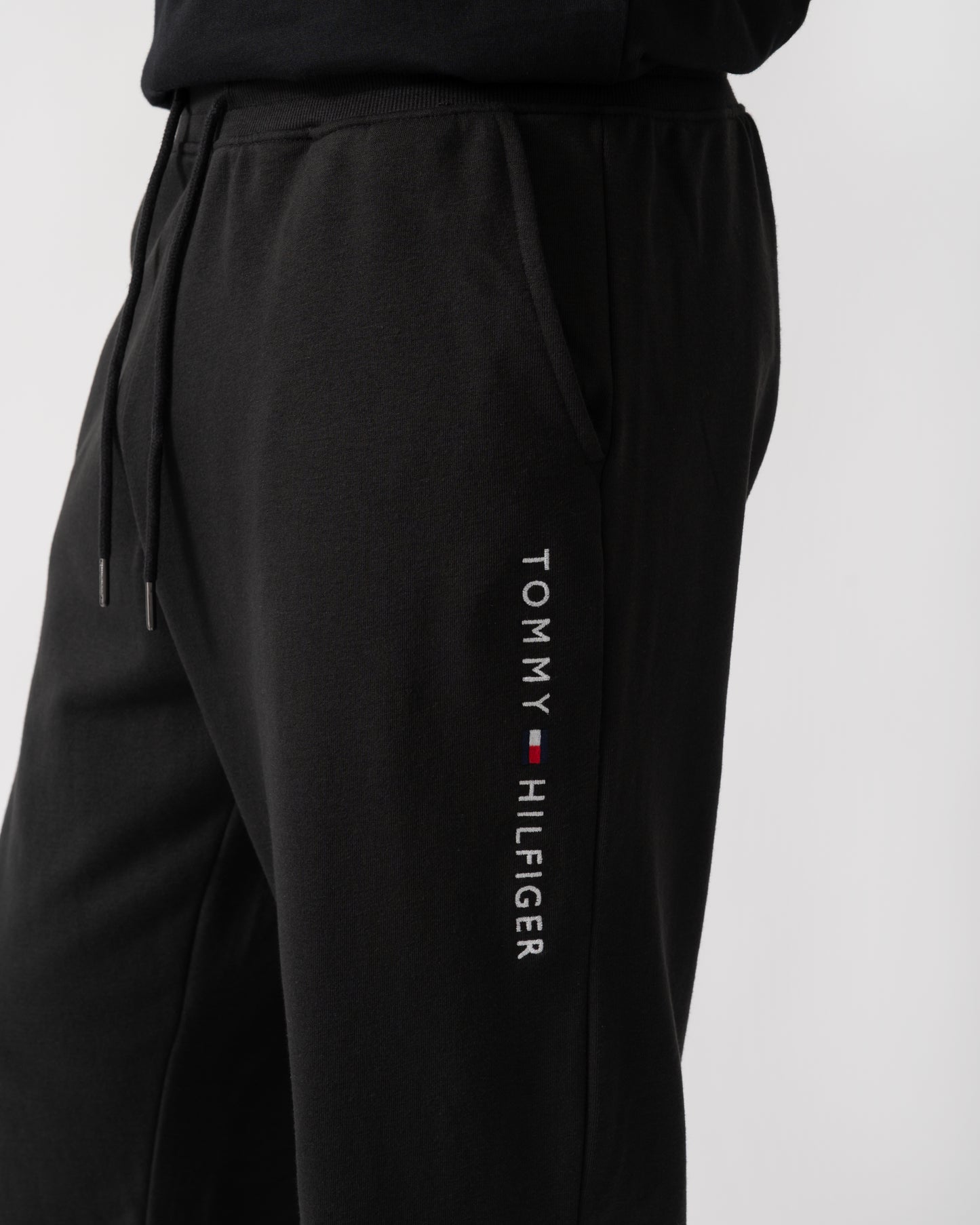 logo shot of a model wearing Tommy Hilfiger Mens Track Joggers in Black