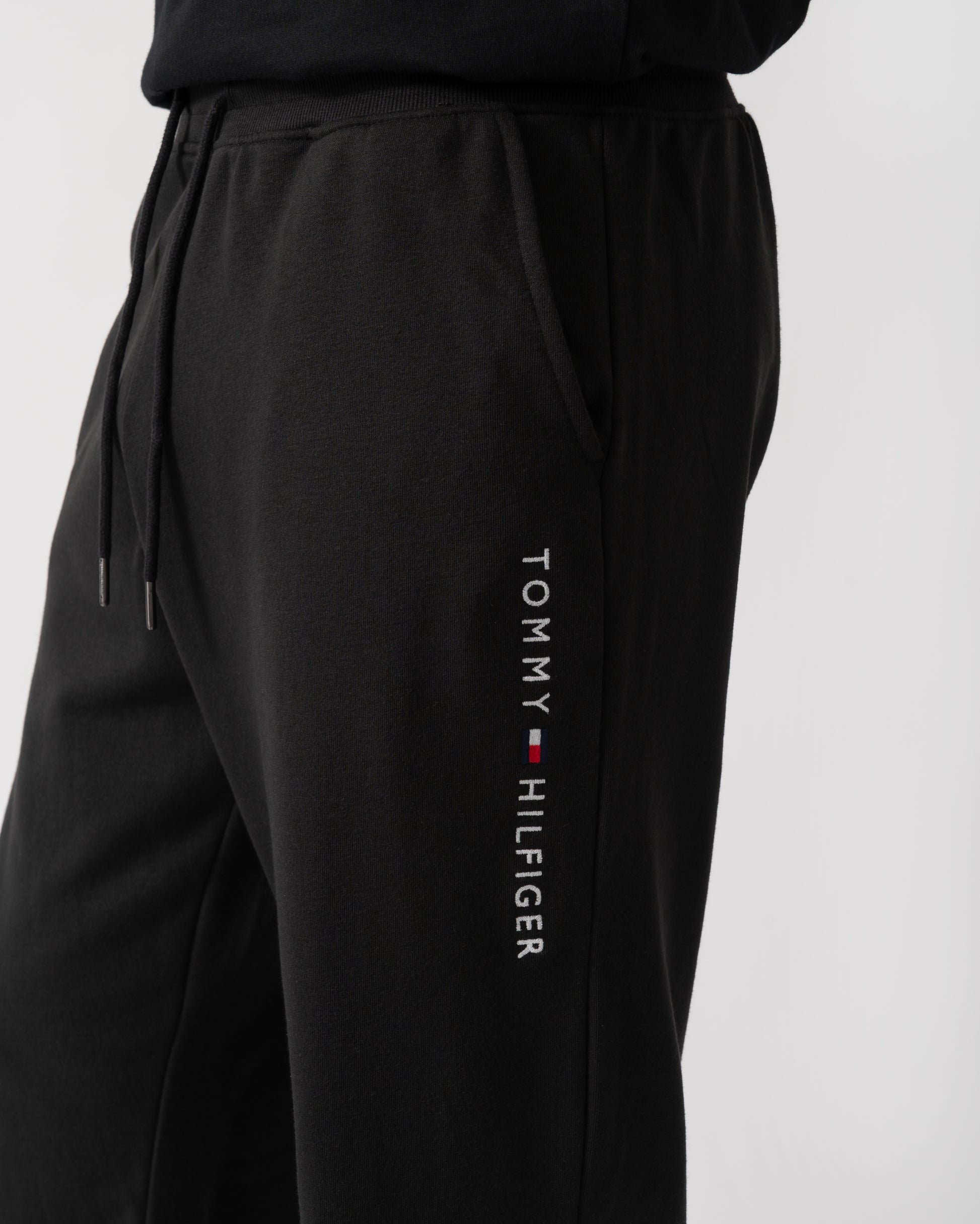 logo shot of a model wearing Tommy Hilfiger Mens Track Joggers in Black