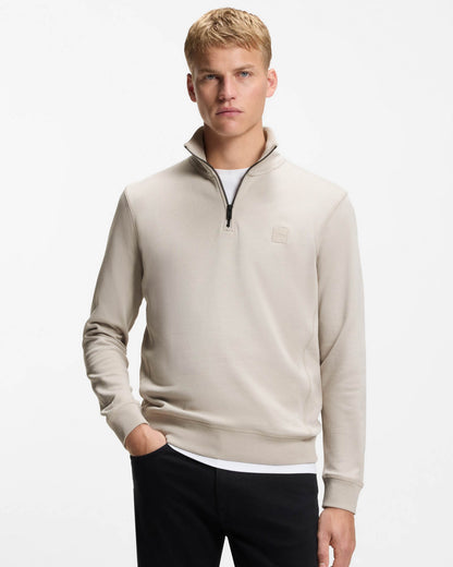 Man wearing a beige half-zip sweatshirt on a white background