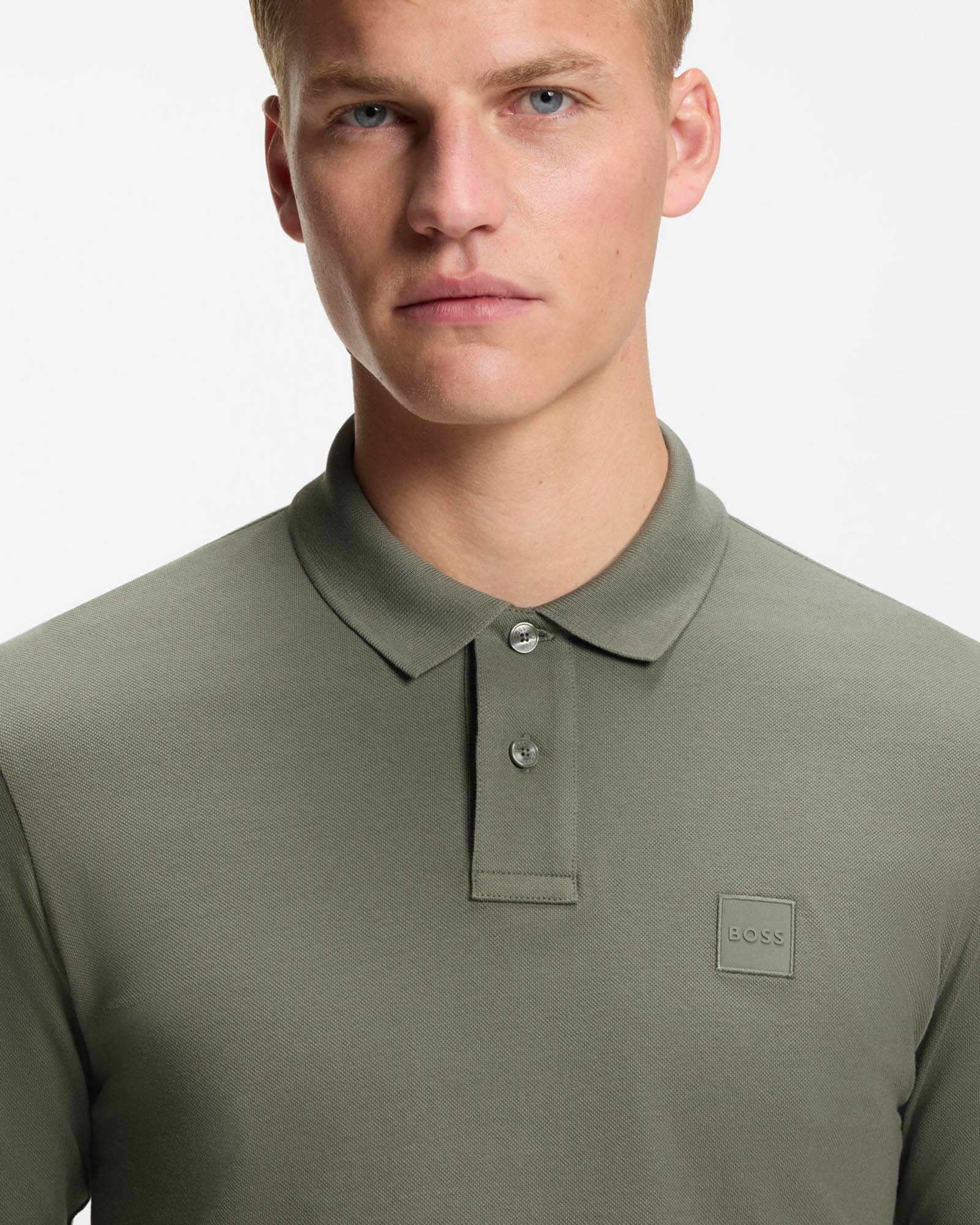Man wearing a green polo shirt with a BOSS logo on a white background