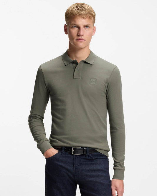 Man wearing a green long-sleeve polo shirt with a logo on a white background