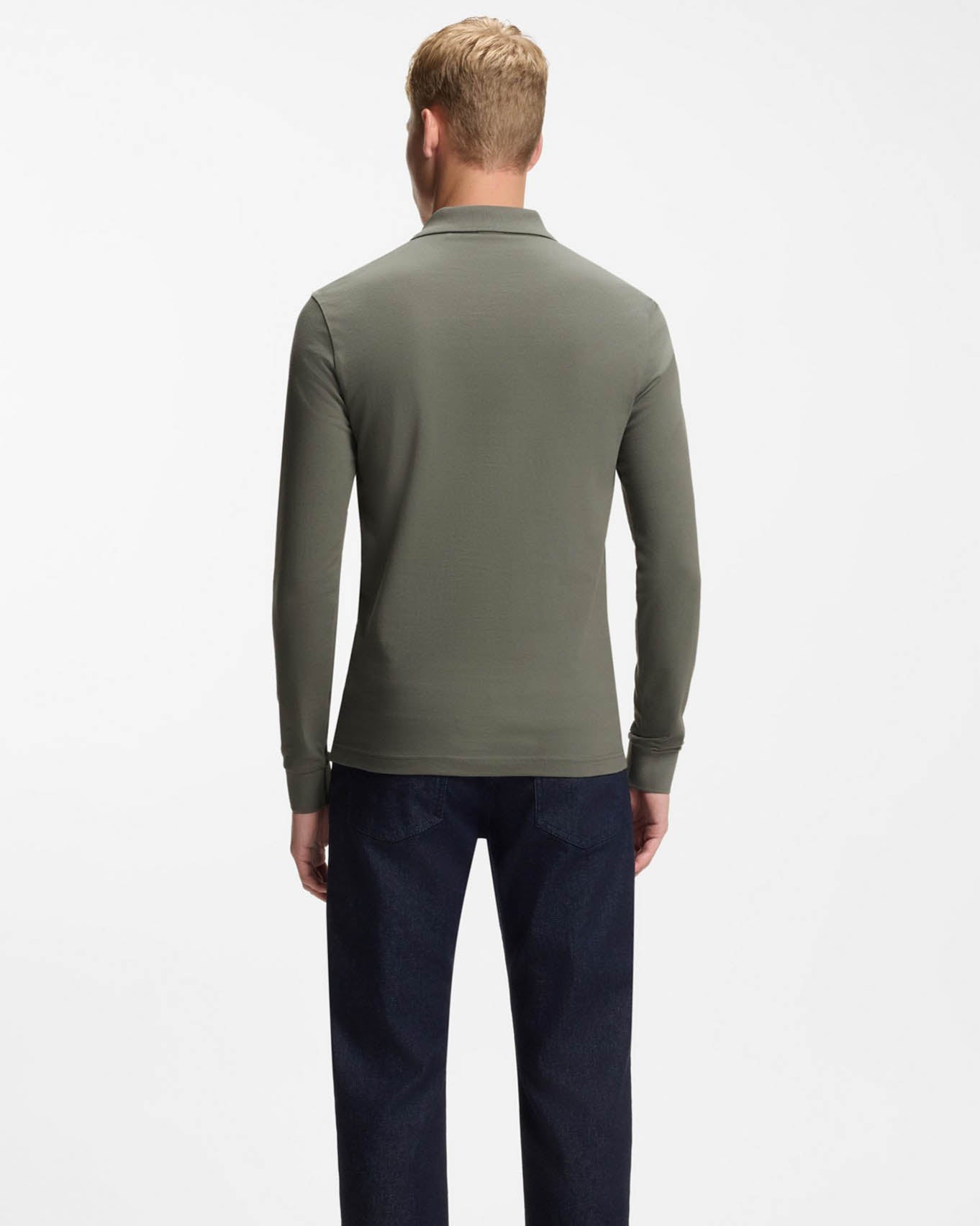 Man wearing a green long-sleeve polo shirt and dark pants on a white background