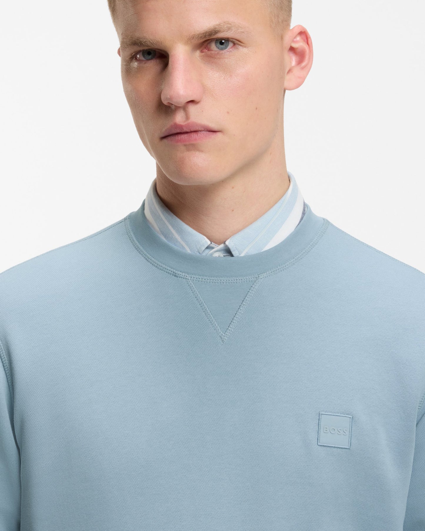 Model wearing BOSS Orange Westart Mens Crew Neck Sweatshirt With Logo Patch in Light/Pastel Blue 458 - Close up