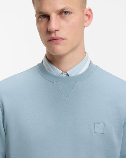 Model wearing BOSS Orange Westart Mens Crew Neck Sweatshirt With Logo Patch in Light/Pastel Blue 458 - Close up